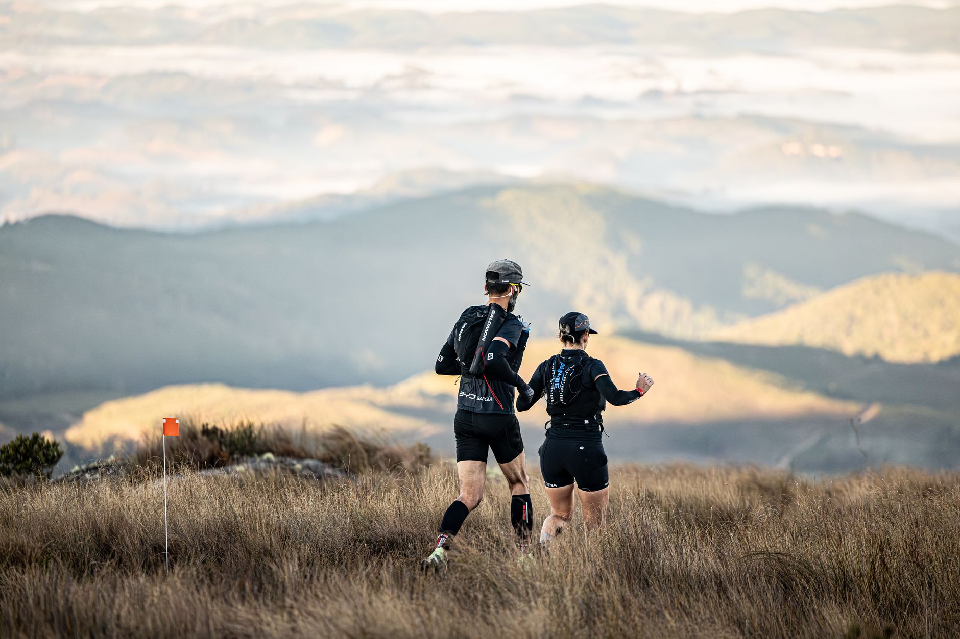 Deux coureurs de sentier naviguant dans un paysage de montagne pittoresque pendant la journée.