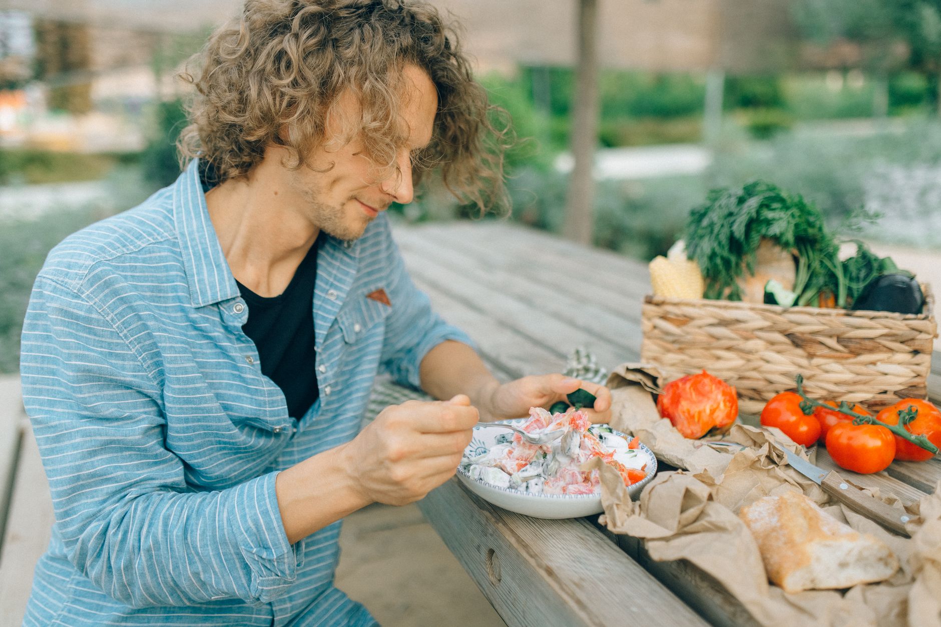 Un homme savoure un repas sain avec des légumes frais à une table de pique-nique extérieure.
